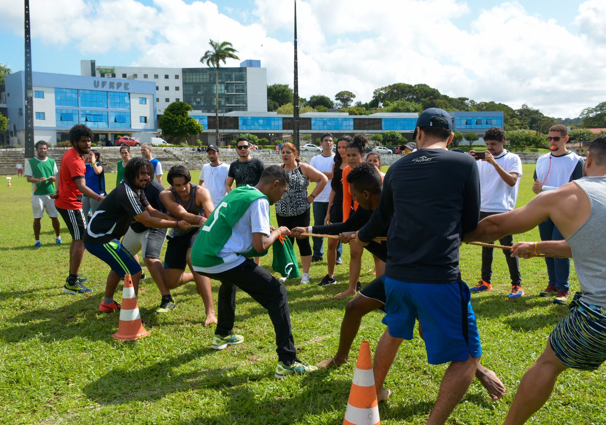 Estudantes do curso de educação física disputando cabo de guerra. Ao fundo, fachada da UFRPE