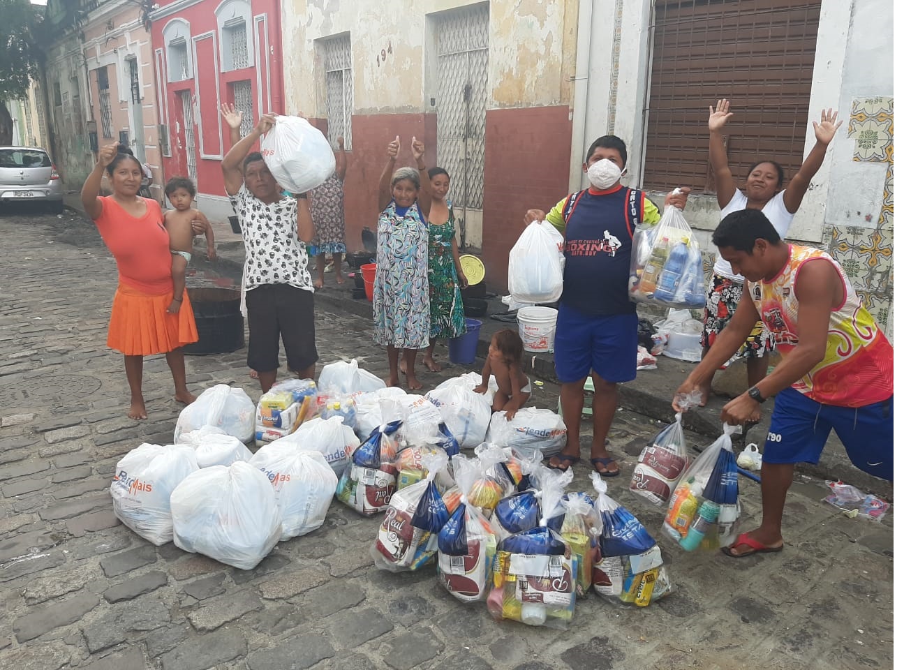 pessoas na rua recebendo alimentos e comemorando